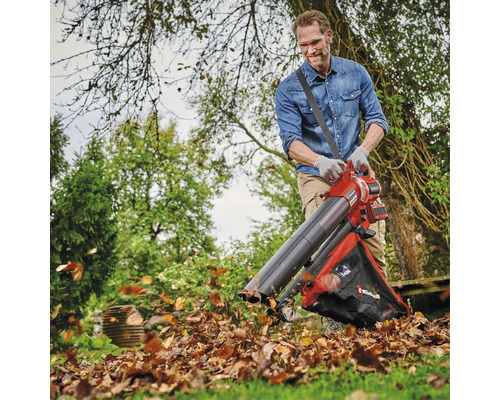 Ein Mann benutzt einen Laubsauger im Garten, um Laub zu entfernen.