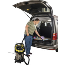 Mann saugt mit einem Mehrzwecksauger den Kofferraum eines Autos aus. Kärcher Logo sichtbar.