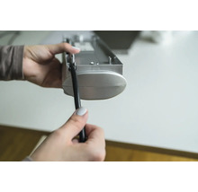 Eine Person hält eine Jalousie und eine Zugschnur in der Hand.