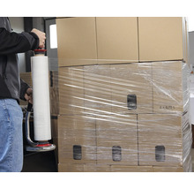 Eine Person wickelt Kartons mit einer Stretchfolienverpackung ein.