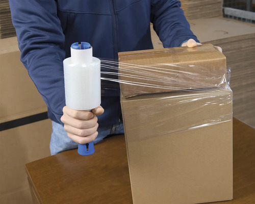 Eine Person verpackt Kartons mit einer Stretchfolienverpackung.