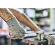 Eine Person trägt Schutzhandschuhe und benutzt einen Schraubenschlüssel.