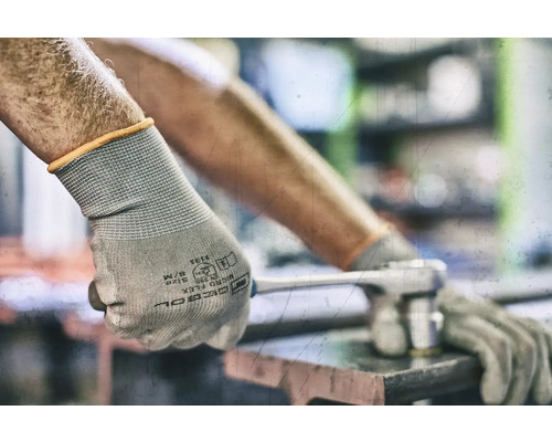 Eine Person trägt Schutzhandschuhe und benutzt einen Schraubenschlüssel.