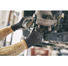 Mechanikerhände arbeiten an einem Autorad mit Schutzhandschuhen.