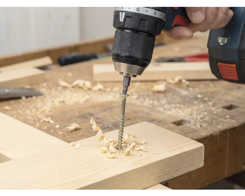 Akkuschrauber schraubt Schraube in Holzbrett