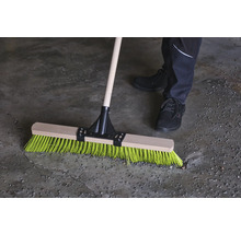 Besen mit Holzstiel und farbigen Borsten im Einsatz