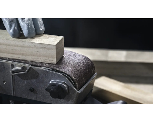 Nahaufnahme eines Bandschleifers beim Glätten eines Holzstücks