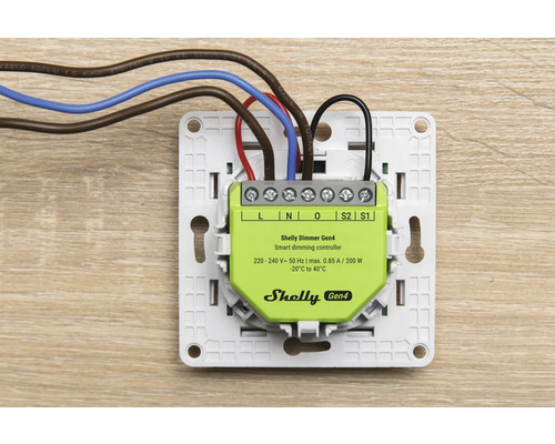 Shelly Dimmer Gen4 Smart-Dimm-Controller in weißem Montagerahmen mit angeschlossenen elektrischen Leitungen für die Unterputzmontage.