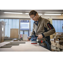 Frau schleift Holzplatte mit einem Exzenterschleifer