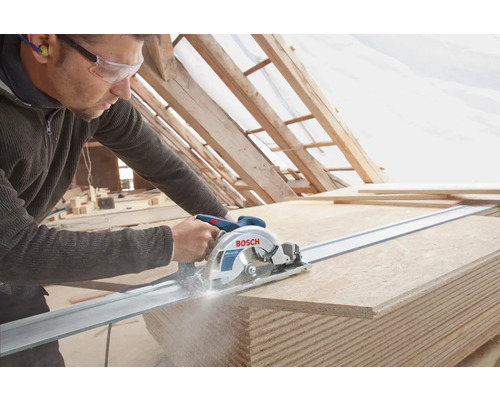 Handwerker sägt mit einer Handkreissäge auf einer Führungsschiene Holzplatten zu. Bosch Logo.