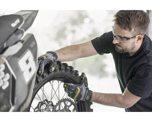 Eine Person montiert mit Arbeitshandschuhen einen Motorradreifen.