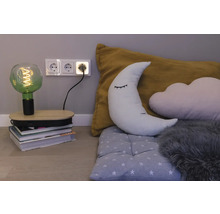 Dekorative LED-Filamentlampe auf einem Bücherstapel in einem Kinderzimmer mit Mondkissen, Wolkenkissen und einer Dreifachsteckdose an der Wand.