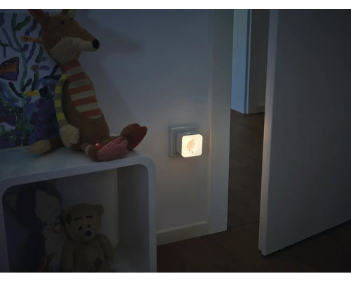 Smarter Zwischenstecker mit integriertem Nachtlicht in einer Wandsteckdose in einem Kinderzimmer.