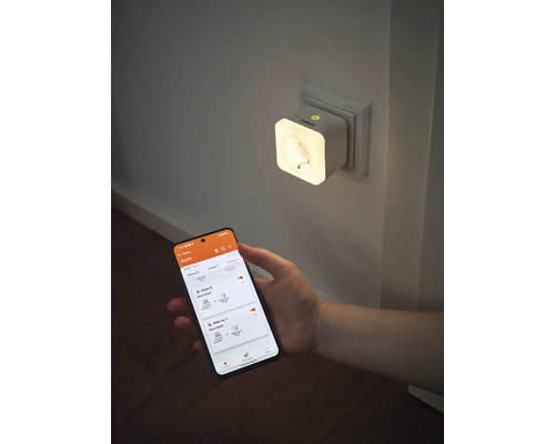 Smarte OSRAM Steckdose mit integriertem Nachtlicht in einer Wandsteckdose, gesteuert über eine App auf einem Smartphone.