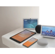 Verschiedene Smart Home Geräte wie Tablet, Smartphone, Smart Displays und Lautsprecher zur Steuerung auf einer hellen Ablagefläche.