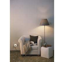 Gemütliche Leseecke mit Sessel, Stehleuchte, Hocker und einer smarten Steckdose in der Wand.