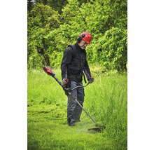 Eine Person benutzt einen Rasentrimmer in einem Garten, geschützt mit einem Helm und Gehörschutz.