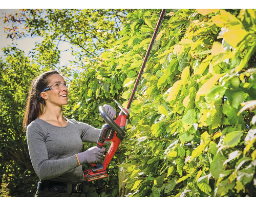 Frau schneidet Hecke mit Akku-Heckenschere von Einhell