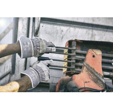 Ein Arbeiter bedient mit Schutzhandschuhen eine Hebemechanik.