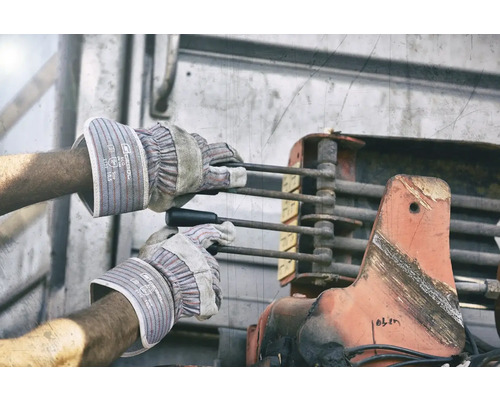 Ein Arbeiter bedient mit Schutzhandschuhen eine Hebemechanik.