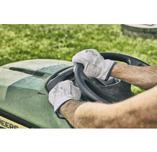 Eine Person fährt einen Rasentraktor und trägt dabei Arbeitshandschuhe.