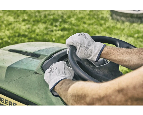 Eine Person fährt einen Rasentraktor und trägt dabei Arbeitshandschuhe.