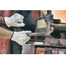 Ein Mann in Arbeitshandschuhen bedient eine Maschine.