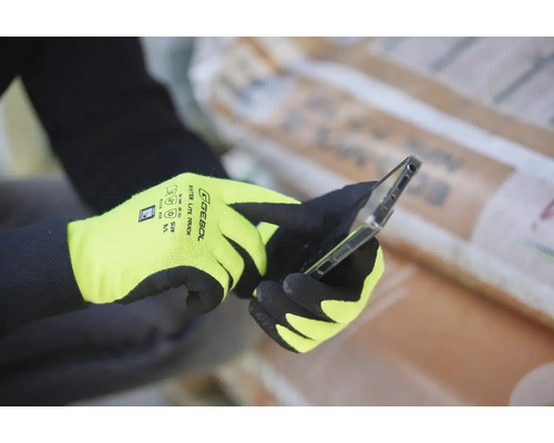 Person mit Montagehandschuhen bedient ein Smartphone.