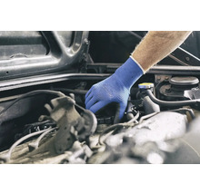 Eine Hand mit Schutzhandschuh inspiziert einen Automotor.