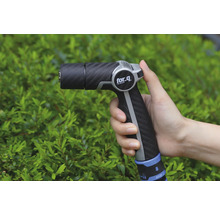 Gartenspritze in der Hand vor Büschen