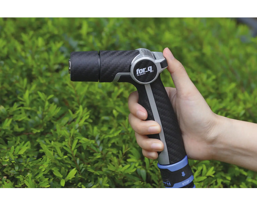 Gartenspritze in der Hand vor Büschen