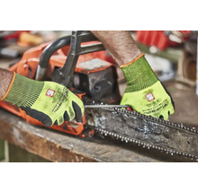 Eine Person, die eine Kettensäge mit Schutzhandschuhen bedient.