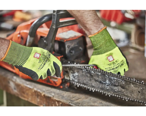 Eine Person, die eine Kettensäge mit Schutzhandschuhen bedient.