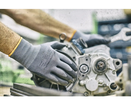 Person mit Montagehandschuhen repariert einen Motorblock mit einem Schraubenschlüssel