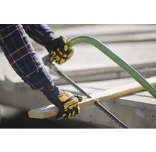 Eine Person sägt ein Stück Holz mit einer Handsäge, während sie Arbeitshandschuhe trägt.