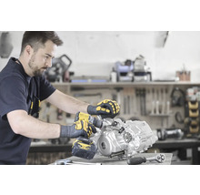 Ein Mann benutzt einen Akku-Bohrschrauber an einem Motorblock in einer Werkstatt