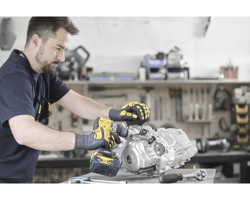 Ein Mann benutzt einen Akku-Bohrschrauber an einem Motorblock in einer Werkstatt