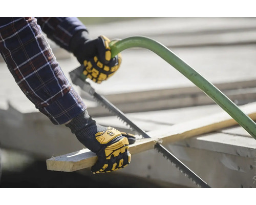 Eine Person sägt ein Stück Holz mit einer Handsäge, während sie Arbeitshandschuhe trägt.