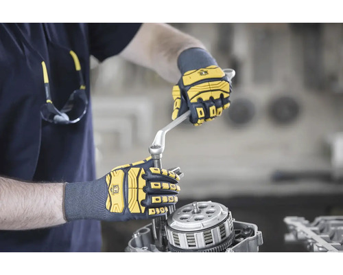 Eine Person repariert mit Handschuhen und Schraubenschlüssel einen Motor.