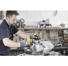 Ein Mann montiert einen Motor mit einem Akku-Bohrschrauber in einer Werkstatt.