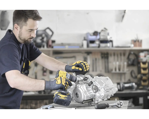 Ein Mann montiert einen Motor mit einem Akku-Bohrschrauber in einer Werkstatt.