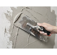 Maurer verputzt Wand mit Glättekelle