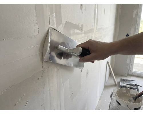 Handwerker glättet Wand mit Glättkelle und Putz