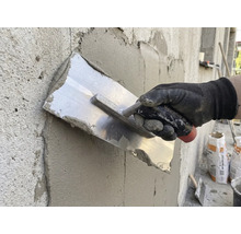 Handwerker glättet Putz mit einer Glättkelle an einer Wand.