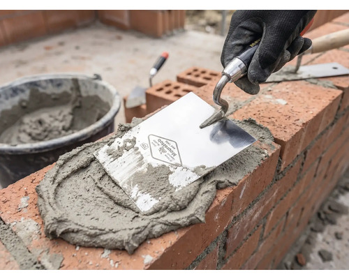 Maurer bei der Arbeit mit Maurerkelle, Mörtel und Ziegeln
