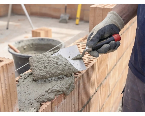Maurer beim Verarbeiten von Mörtel und Ziegelsteinen für den Wandbau