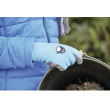Eine Person trägt Gartenhandschuhe mit Pinguin-Motiv und hält einen Eimer.