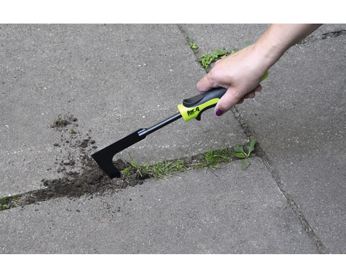 Eine Hand benutzt eine Fugenkratzer zur Unkrautentfernung zwischen Pflastersteinen.