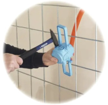 Montage einer blauen Elektrodose an einem Metallgitter mit einem Hammer.