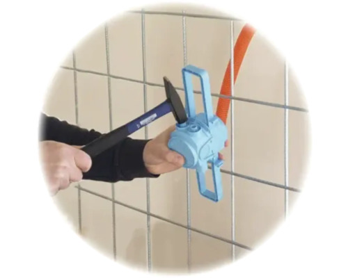 Montage einer blauen Elektrodose an einem Metallgitter mit einem Hammer.